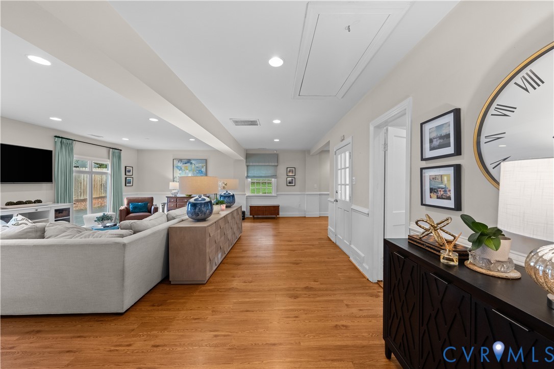 Open-concept living space featuring wood-finish flooring, recessed lighting, and crisp white wainscoting