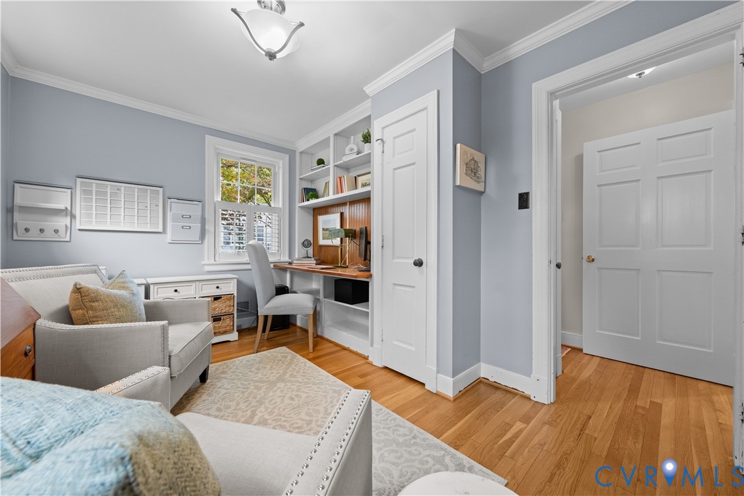 Built-in floor-to-ceiling shelving, custom wood desk surface, wood-finish flooring, six-panel interior doors, and crown molding