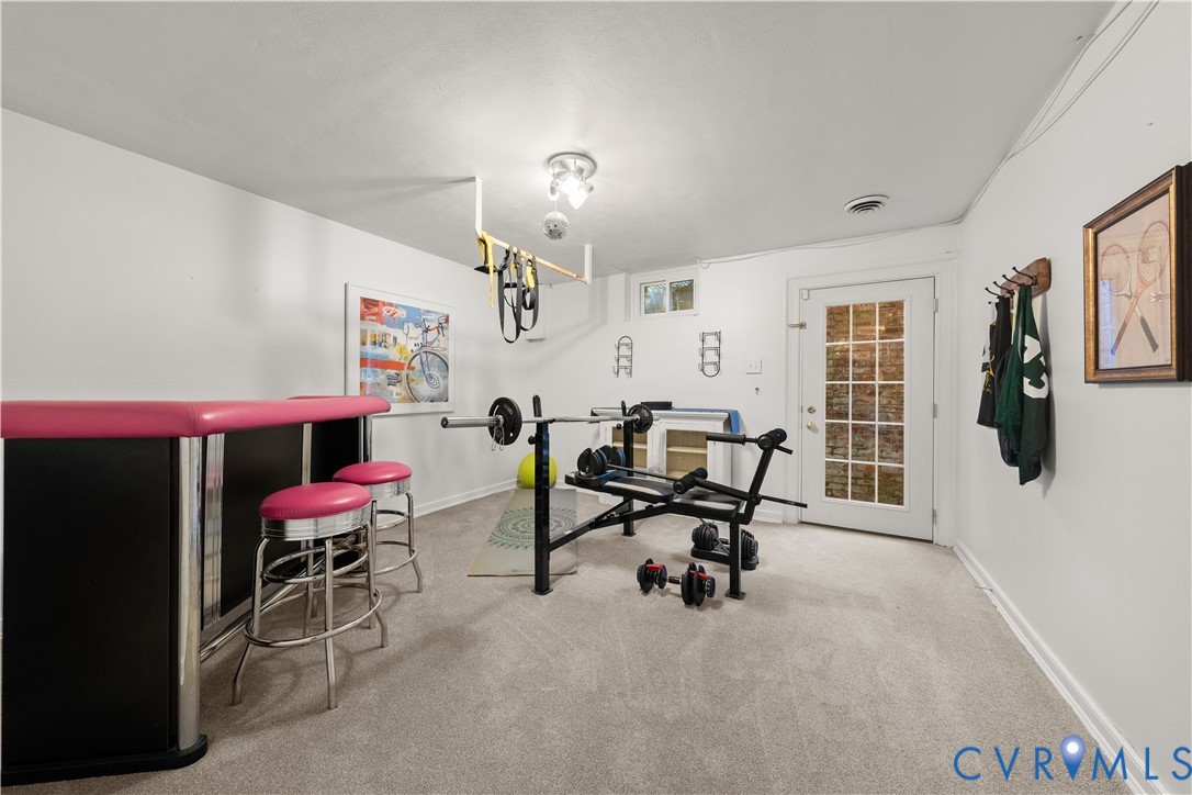 Neutral-toned room featuring neutral carpeting, a multi-light ceiling fixture, and a white exterior door with glass pane detailing