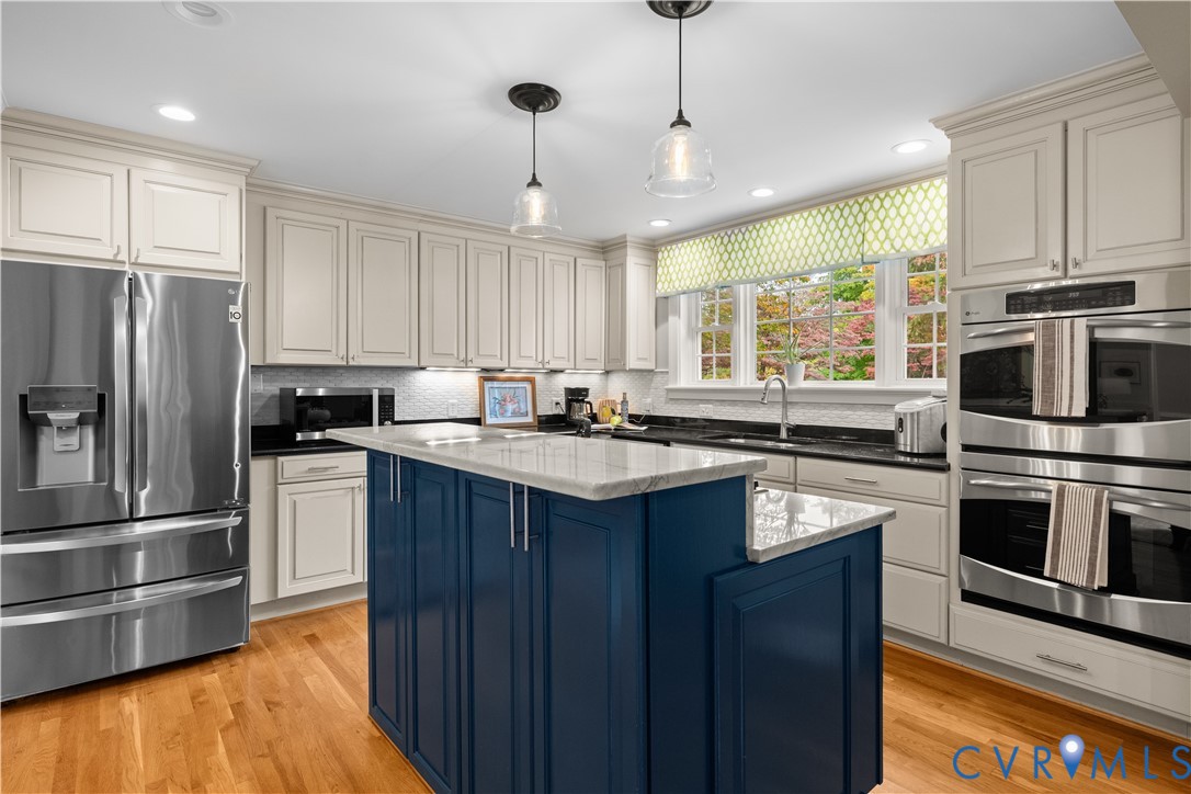 Kitchen featuring a central island with blue cabinetry, stone countertops, stainless steel appliances, recessed lighting, and wood-finish flooring