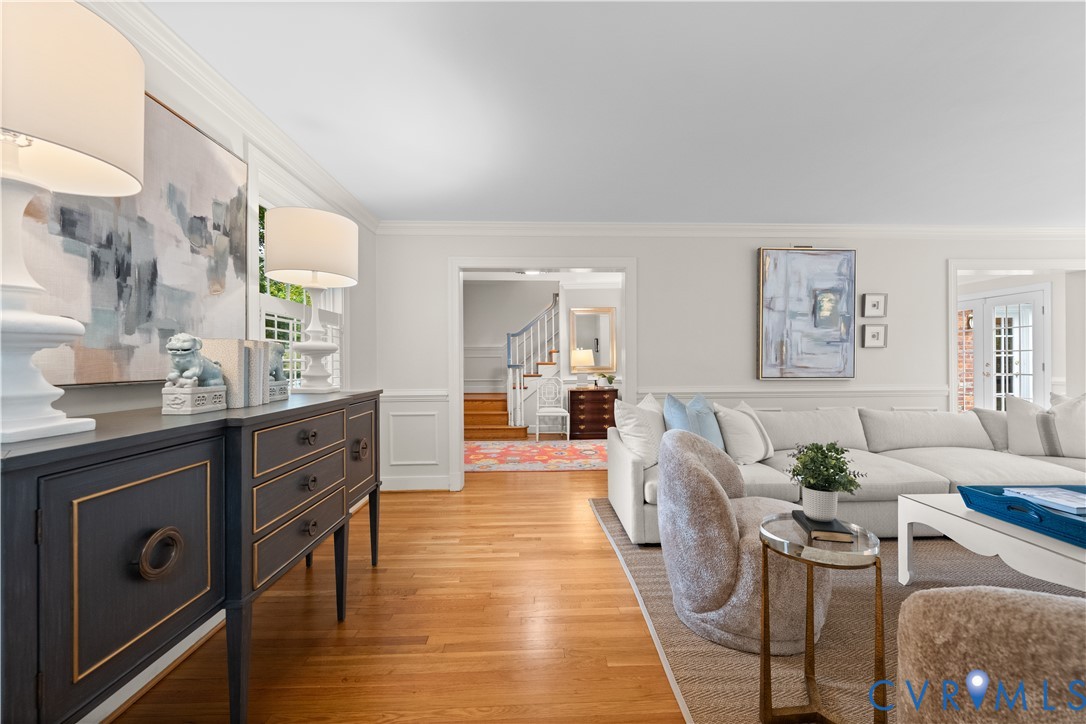 Living area featuring wood-finish flooring, crown molding, wall paneling, and a multipane glass door