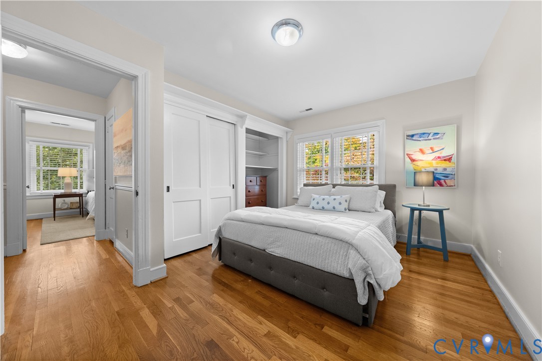 Wood-finish flooring, white paneled closet doors, built-in recessed shelving, and multi-pane windows with trim casing