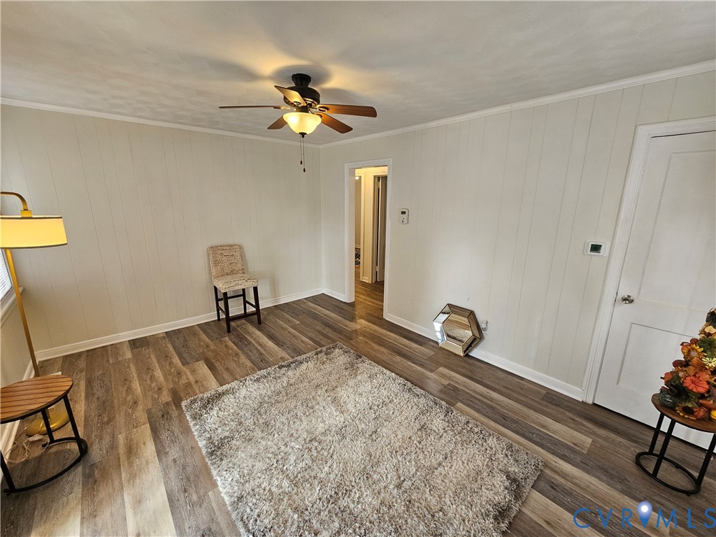 Neutral-toned vertical paneling, wood-finish flooring, and ceiling-mounted fan with integrated light fixture