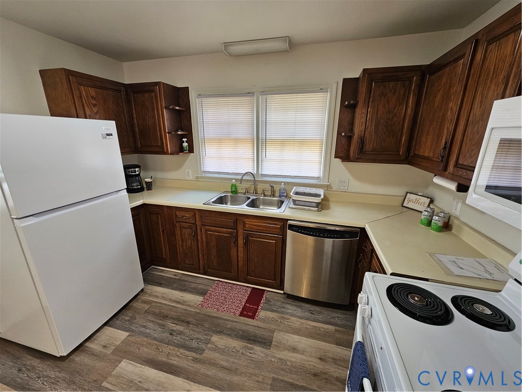 Kitchen featuring wood-finish cabinetry, stainless steel dishwasher, double-basin sink, and wood-finish flooring