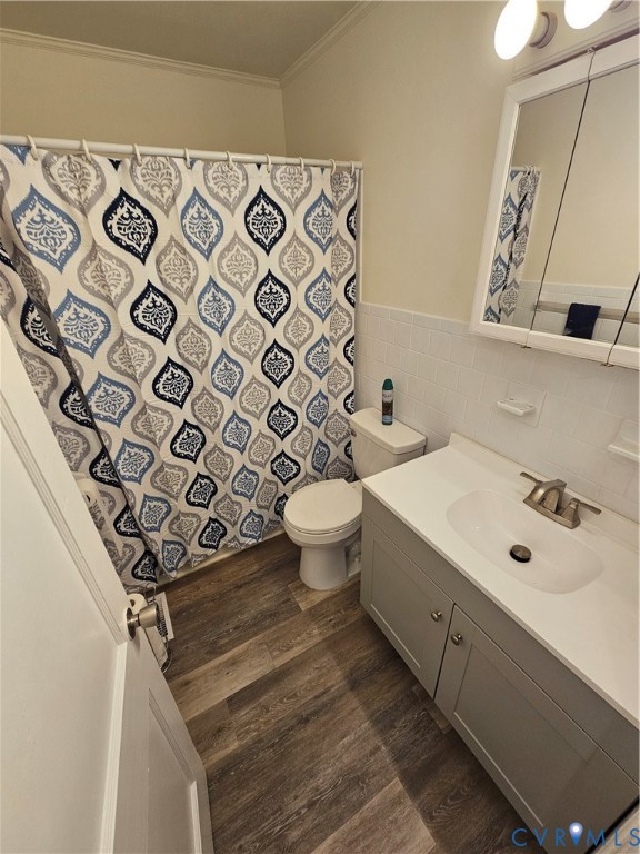 Bathroom featuring wood-finish flooring, a vanity with a solid-surface countertop and integrated sink, a tiled tub surround, and a medicine cabinet with mirrored doors