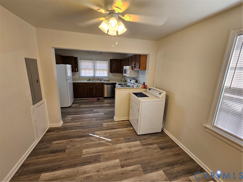 Wood-finish flooring throughout, kitchen featuring dark wood cabinetry, stainless steel dishwasher, integrated sink, and ceiling-mounted light fixture