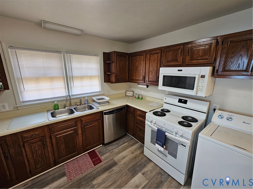 Kitchen featuring stained wood cabinetry, wood-finish flooring, dual-basin stainless steel sink, and white appliances
