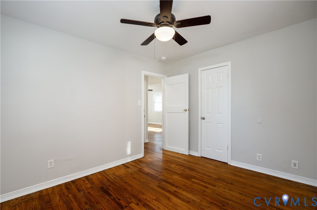Room featuring wood-finish flooring, neutral wall paint, and a ceiling-mounted fan with integrated lighting