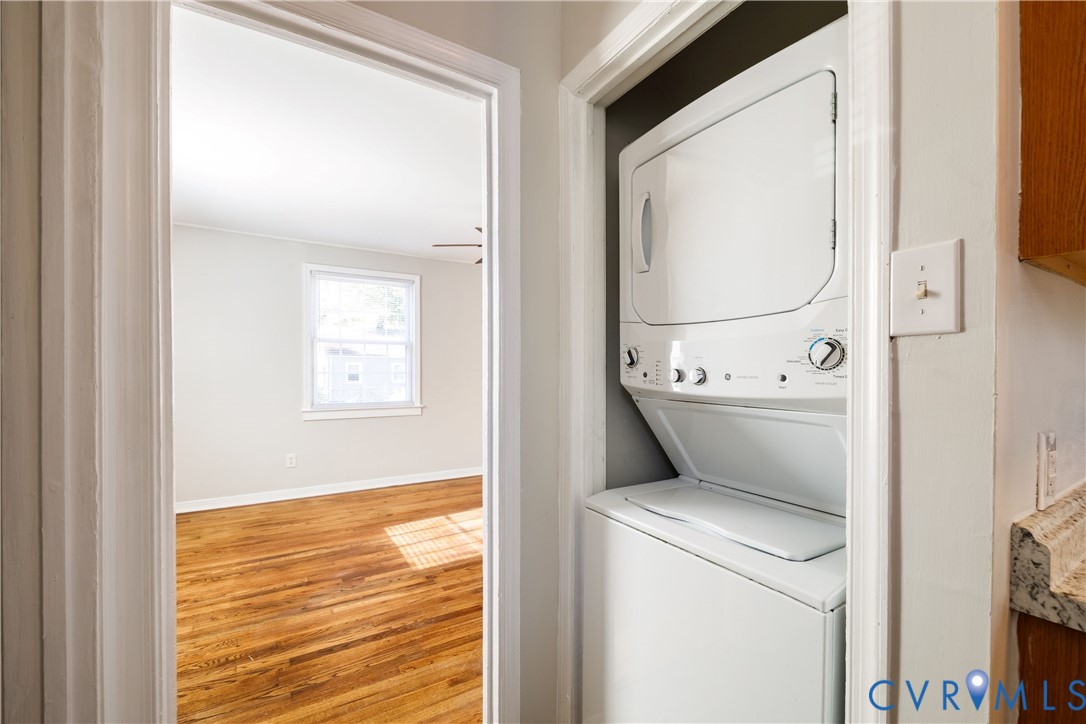 Built-in stacked laundry unit, wood-finish flooring, and natural light from a double-hung window Built-in stacked laundry unit, wood-finish flooring, and natural light from a double-hung window