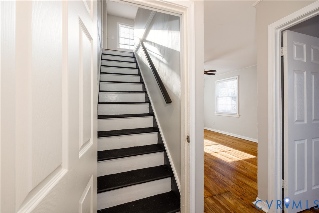 Staircase with high-contrast painted treads, wood-finish flooring, multi-pane windows, and six-panel interior doors