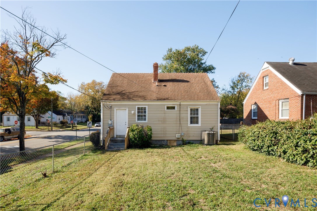 Exterior profile featuring horizontal siding, a central masonry chimney, and a rear staircase with wood railings