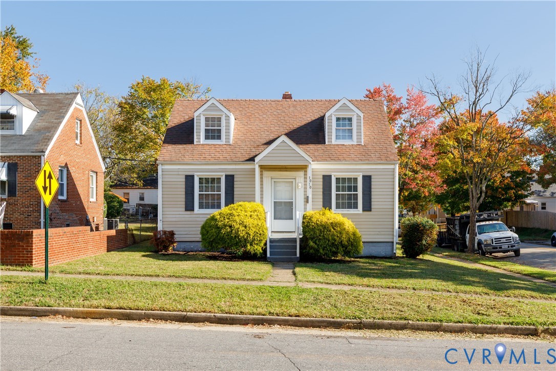 Cape Cod style exterior featuring horizontal siding, twin dormer windows, a covered front entryway, and dark window shutters Cape Cod style exterior featuring horizontal siding, twin dormer windows, a covered front entryway, and dark window shutters