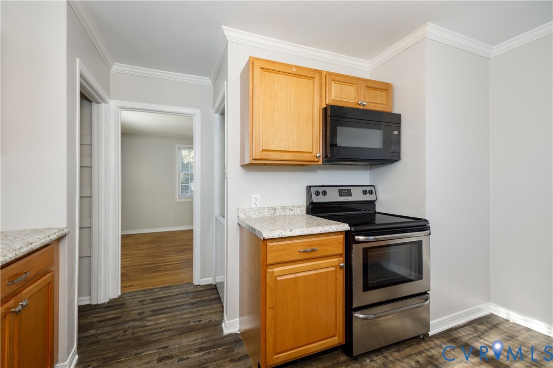 Kitchen featuring wood cabinetry, stone-finish countertops, stainless steel range, and over-the-range microwave, with wood-finish flooring Kitchen featuring wood cabinetry, stone-finish countertops, stainless steel range, and over-the-range microwave, with wood-finish flooring