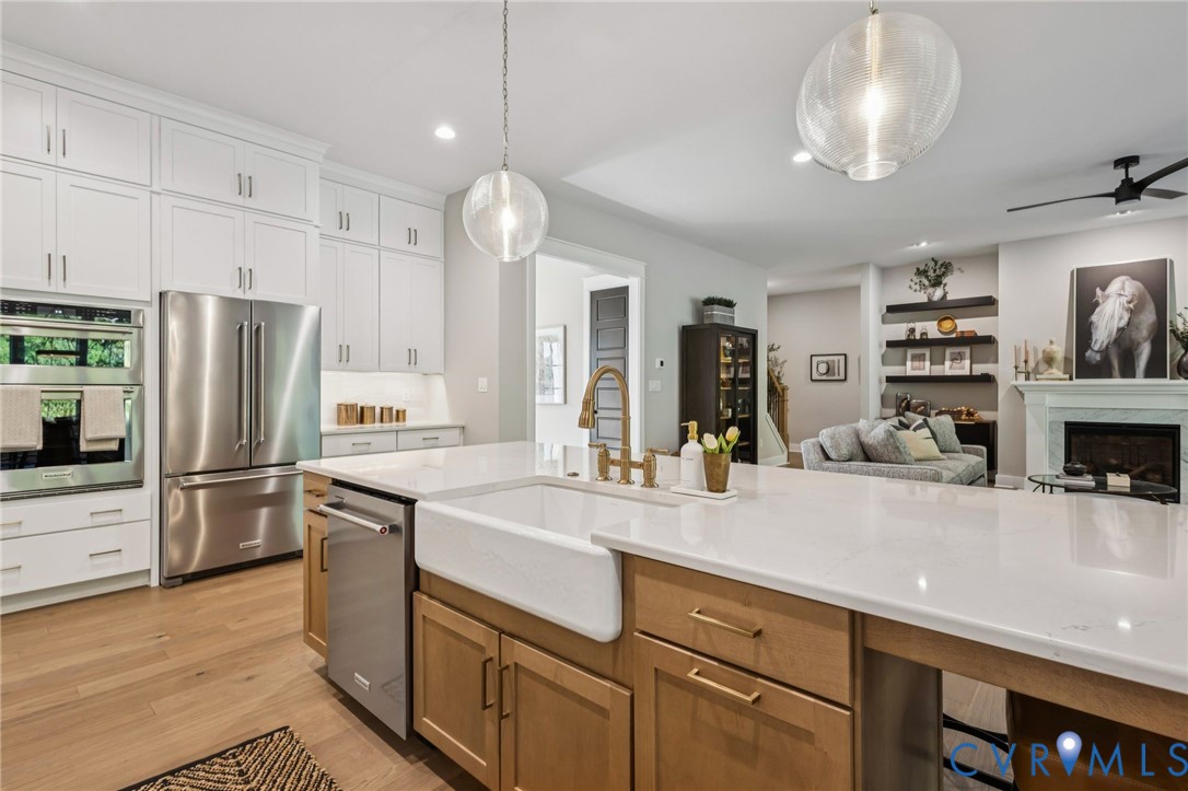 Spacious kitchen featuring an expansive island with a farmhouse sink, light wood-finish cabinetry, and quartz countertops