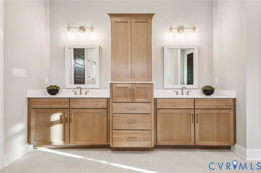 Dual vanity with light wood-finish cabinetry, white countertops, and brushed nickel fixtures