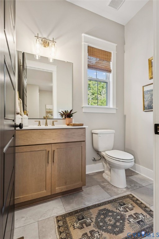 Bathroom featuring a wood-finish vanity with a white countertop, wall-mounted mirror, and brass-tone vanity light