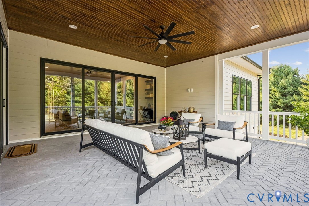 Spacious covered patio featuring a wood-finish ceiling, ceiling fan, and herringbone-patterned flooring