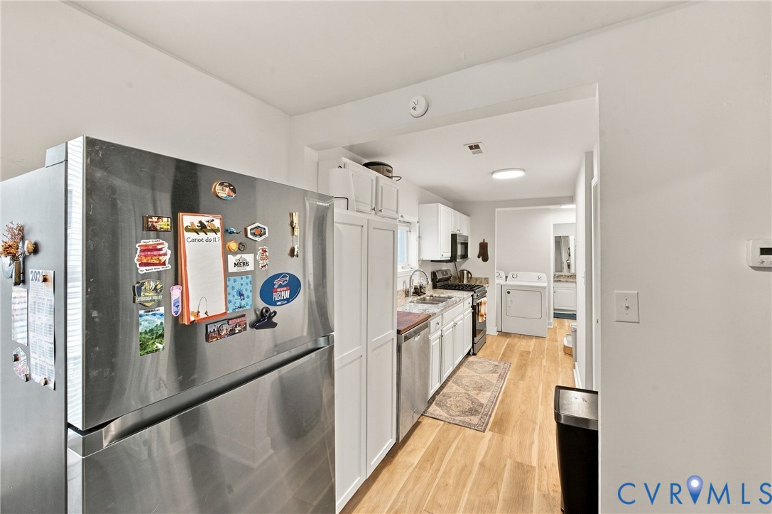 Kitchen featuring white cabinetry, wood-finish flooring, stainless steel appliances, and recessed lighting