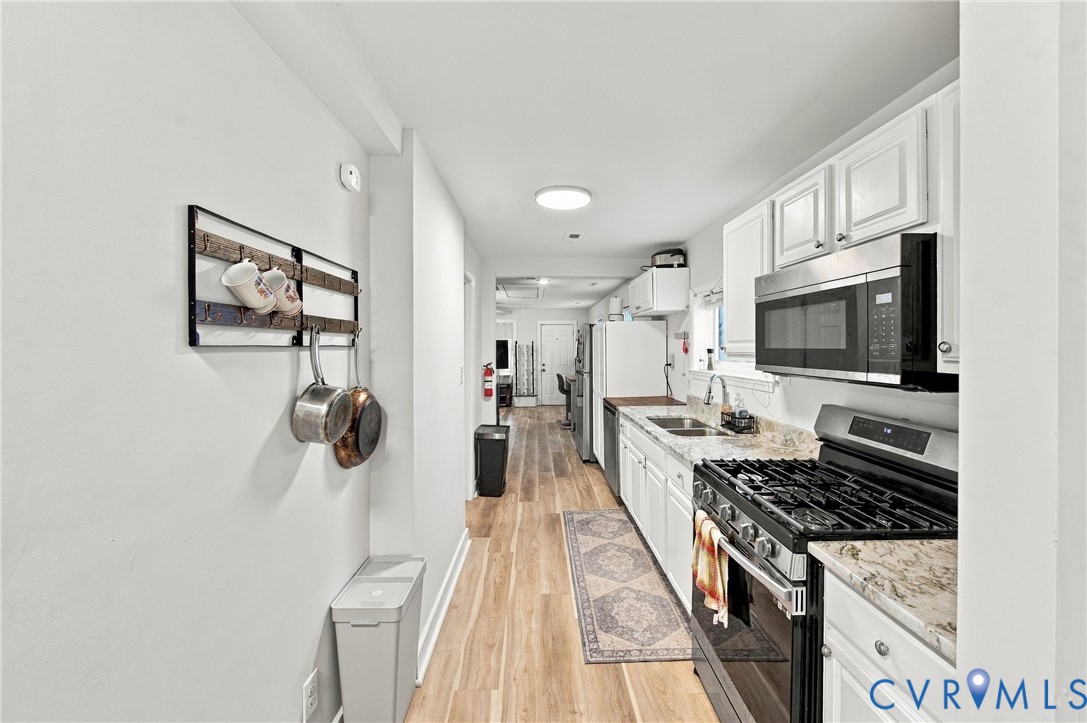 Kitchen featuring white cabinetry, stone-finish countertops, stainless steel appliances, and wood-finish flooring