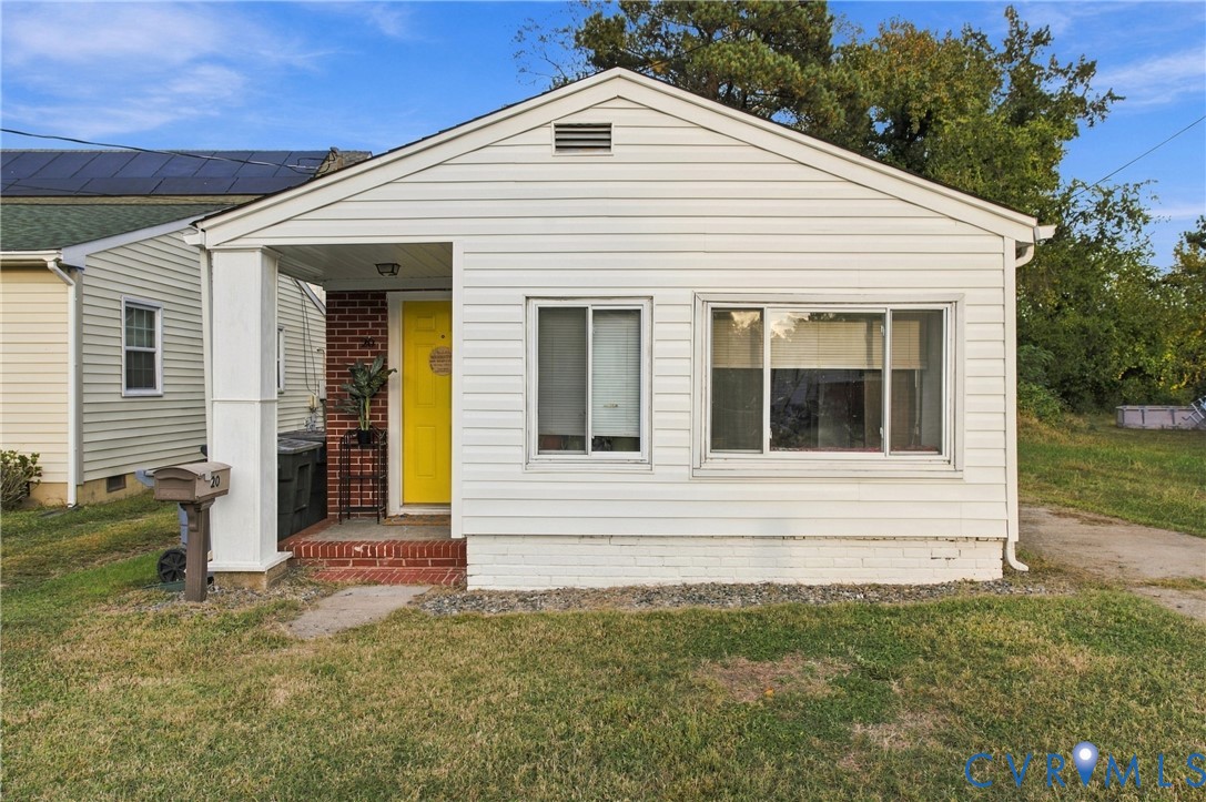 Exterior featuring horizontal siding, a covered front porch with a brick stoop, and a brick accent wall at the entry