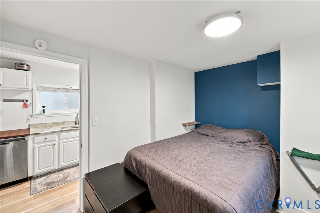 Room featuring an accent wall, wood-finish flooring, and a flush-mount ceiling light fixture