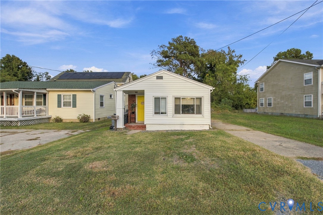 Single-story exterior featuring white vinyl siding, a covered front entryway, and a concrete driveway