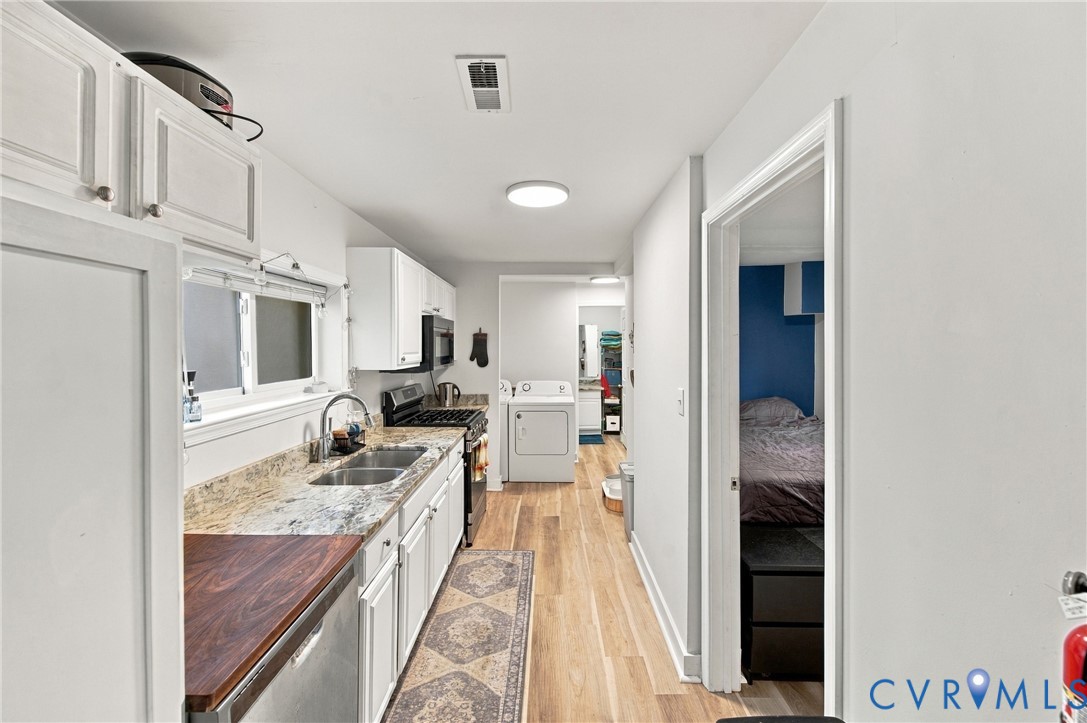 Kitchen featuring white cabinetry, stone-surface countertops, dual-basin stainless steel sink, and wood-finish flooring