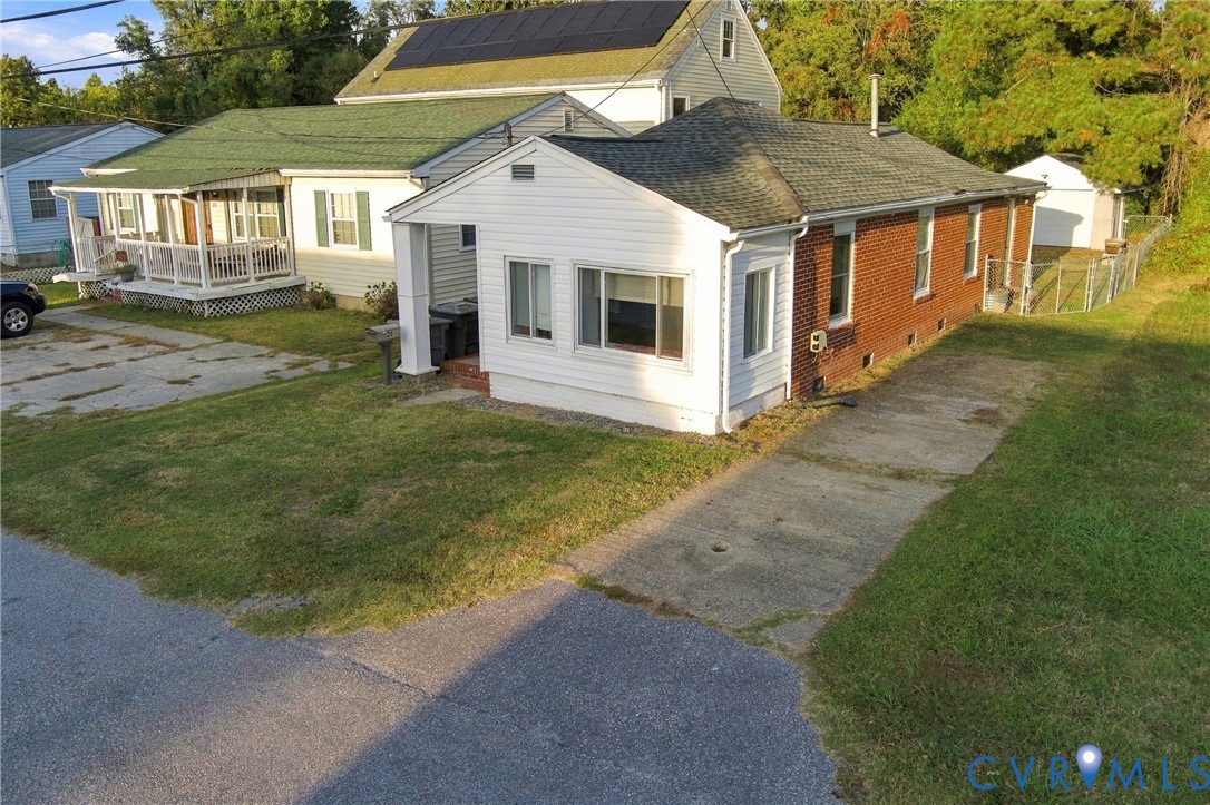 Single-story exterior featuring a brick and vinyl facade, asphalt shingle roofing, integrated solar panels, and an attached concrete driveway