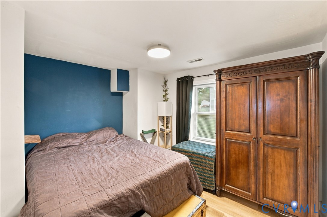 Room featuring a bold blue accent wall, neutral wall coloring, wood-finish flooring, and a window with casing