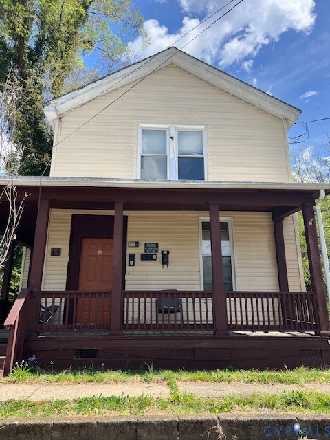 Two-story exterior featuring light-toned horizontal siding, a covered front porch with dark-finished wooden railings and support posts, and double-hung windows