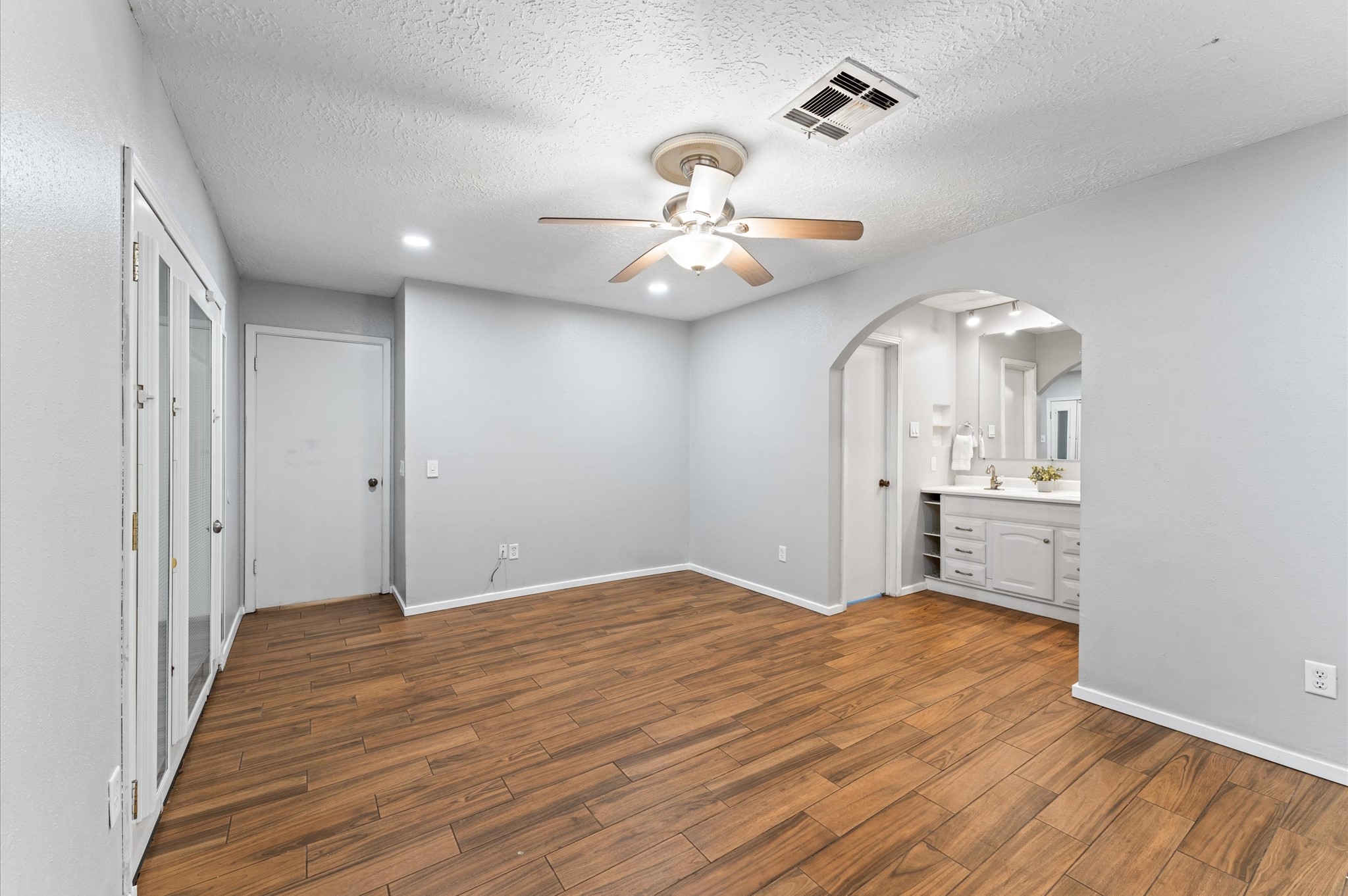 Another view of the primary bedroom with french doors to patio