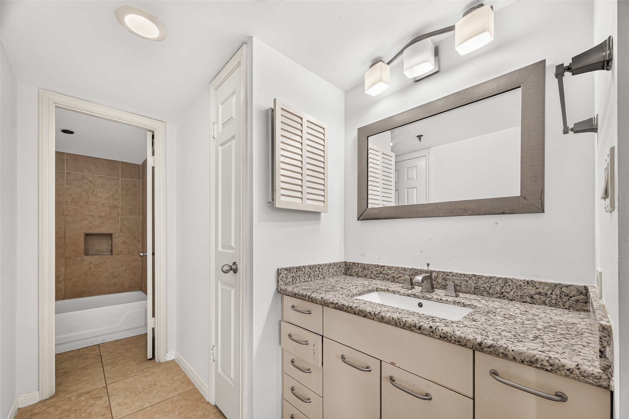 Primary bathroom with granite counter top, linen closet and walk in closet
