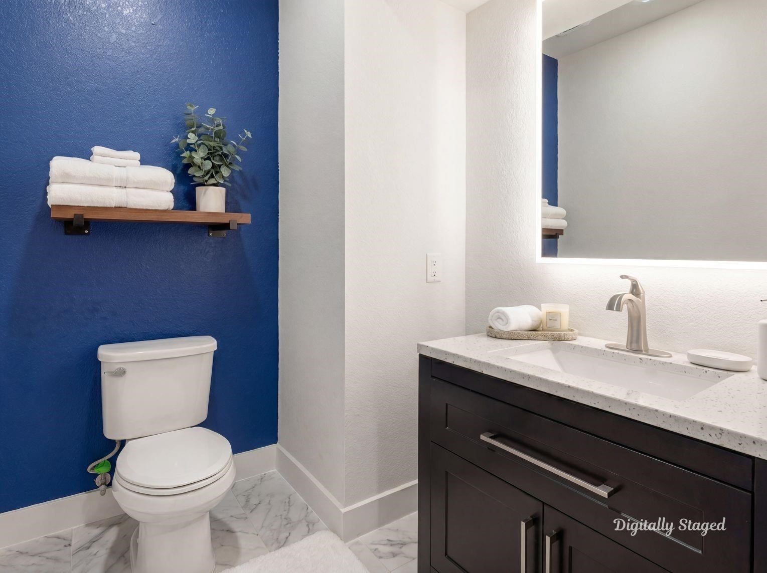A stylish half-bath or secondary
bathroom featuring a bold blue
accent wall, a dark vanity with a
stone countertop, a modern backlit
mirror, and marble-look tile floors.
This photo has been digitally staged
to illustrate the possibilities of the
homes aesthetic and potential
design. Some furnishings and dcor
shown are for visual inspiration.