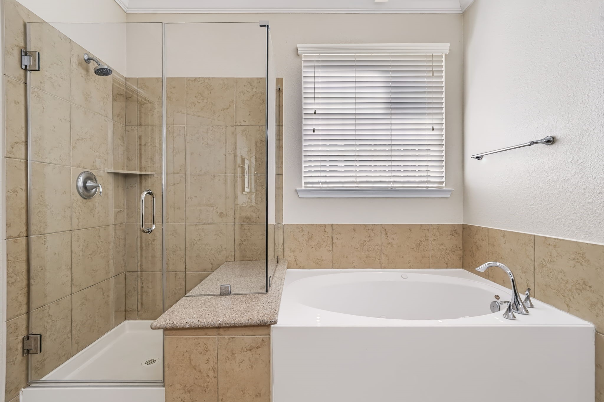 A newly updated walk-in shower with a frameless glass enclosure and granite bench seat pairs beautifully with a round soaking tub, creating a spa-like retreat for relaxation.