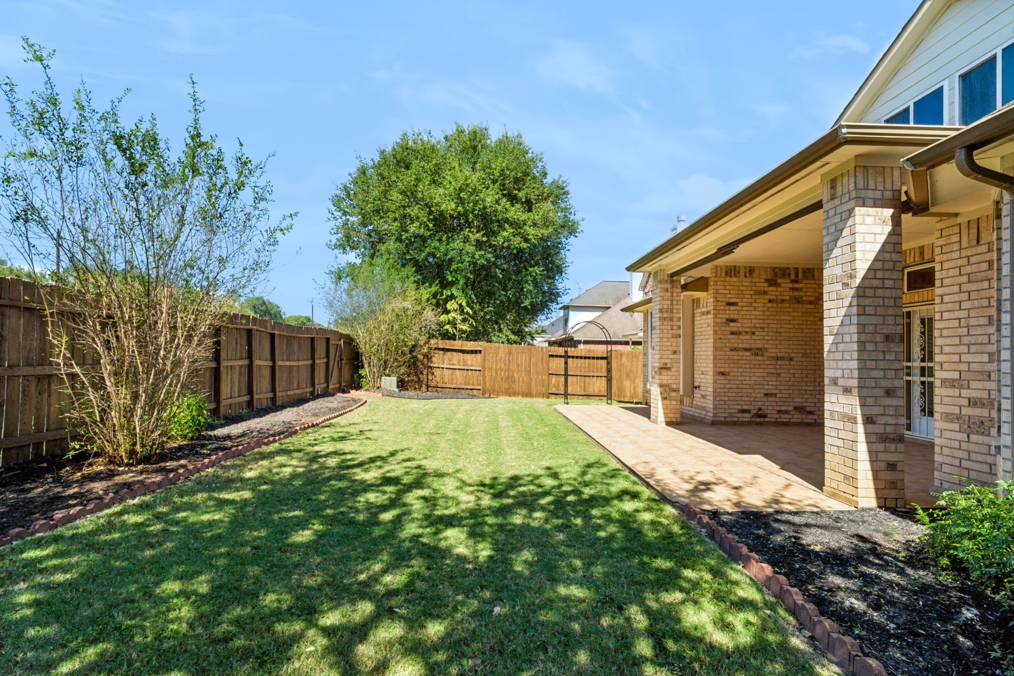 Fenced backyard with grassy lawnperfect for children and outdoor activities.