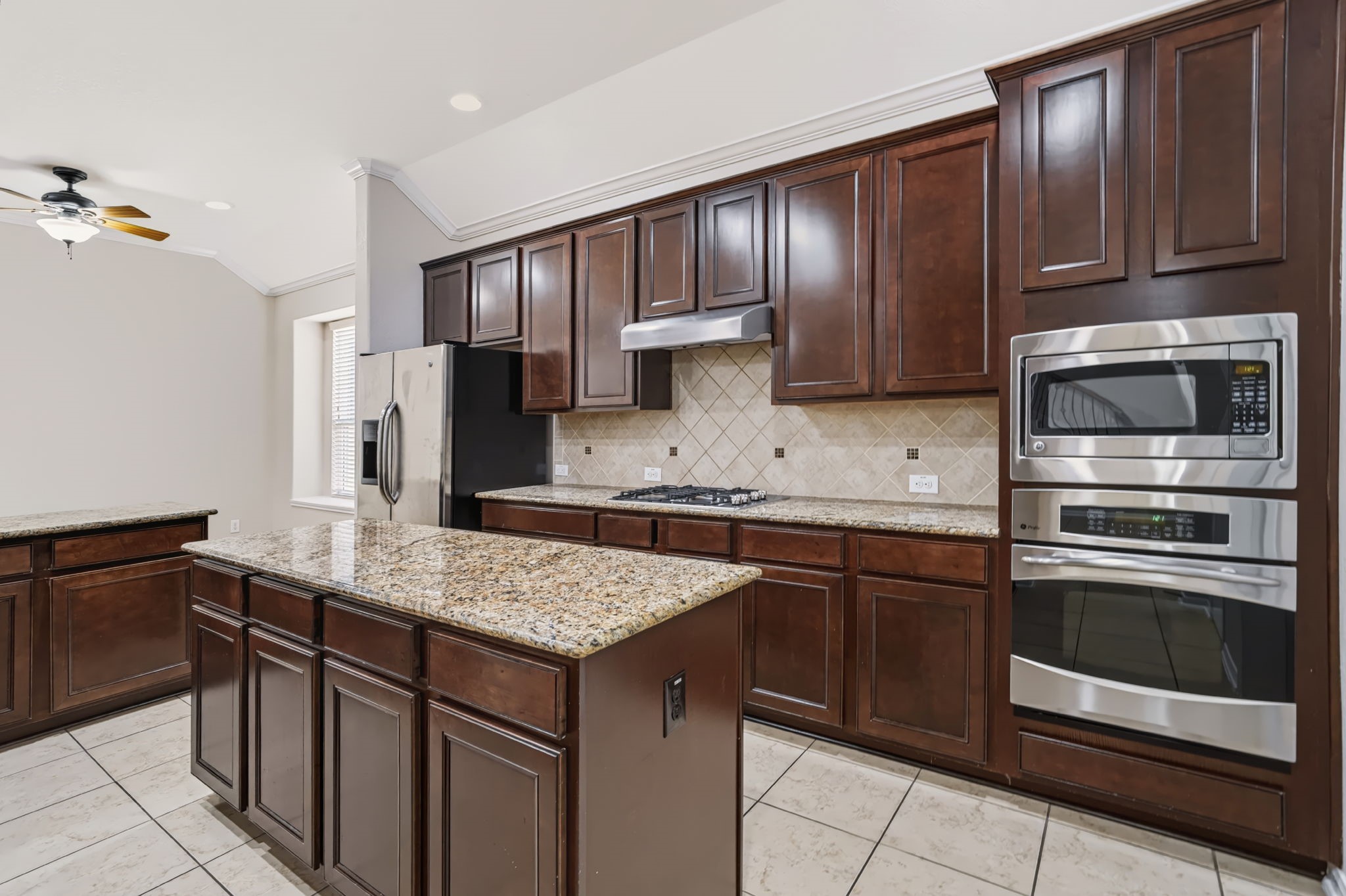 The kitchen features a built-in stainless steel gas cooktop, convection oven, and microwave.