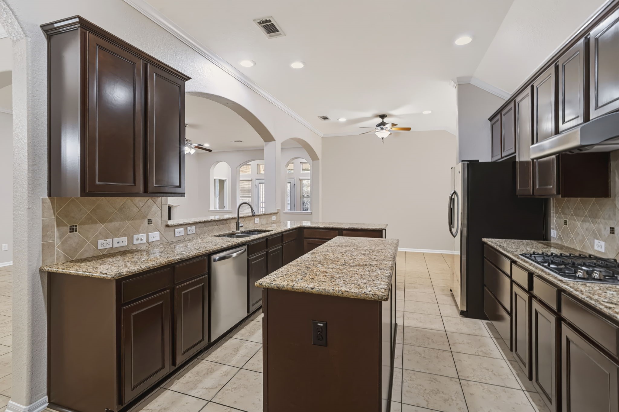 Center island with granite countertops, tile backsplash, and abundant counter space and cabinetry, offer ample storage and a functional layout for meal preparation.