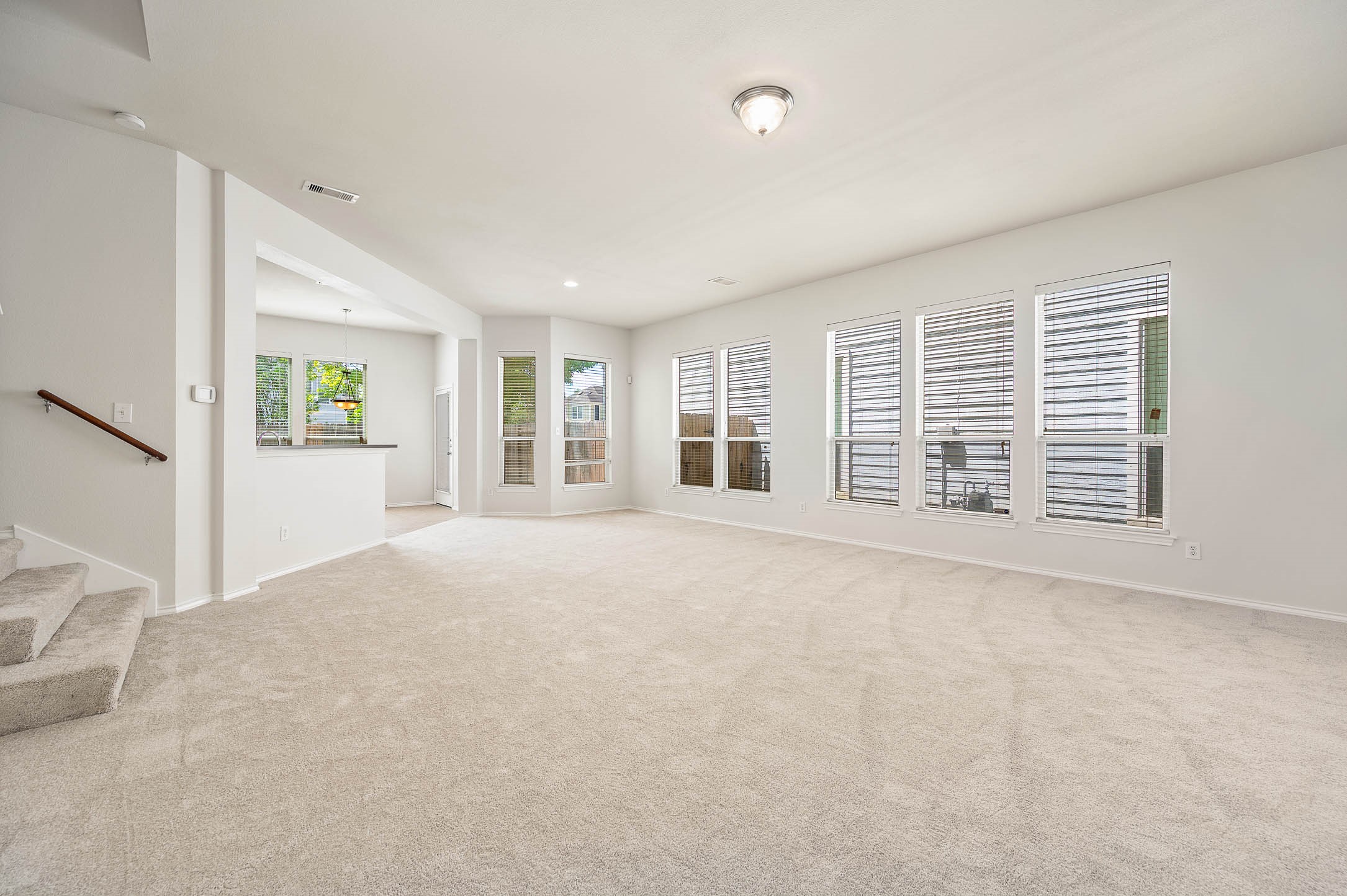Spacious living area features new neutral color carpeting, ample natural light from multiple windows, and an open floor plan leading to the kitchen/dining, Ideal for family gatherings and entertaining.