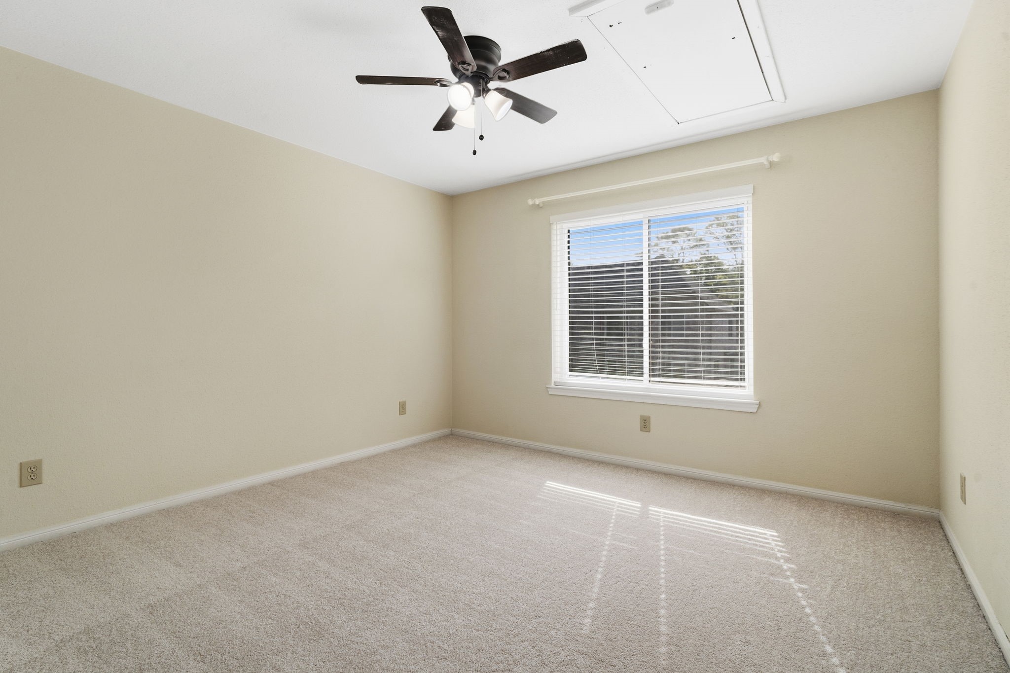 A generously sized secondary bedroom with natural light, ceiling fan & attic access.