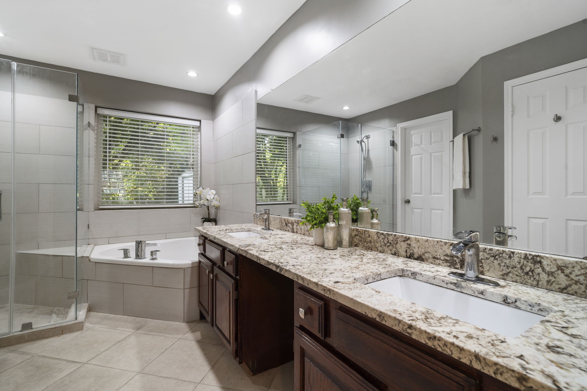 An expansive dual vanity offers generous counter space & storage, complemented by a full-width mirror that enhances the primary baths bright, open feel.