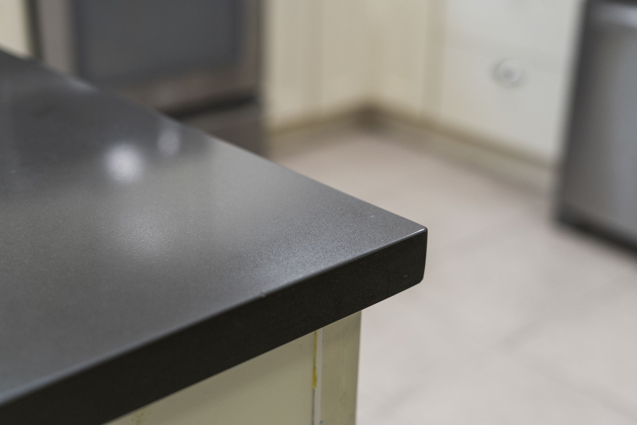 Sleek dark countertops add a modern contrast to the white cabinetry, creating a clean & polished finish throughout the kitchen.