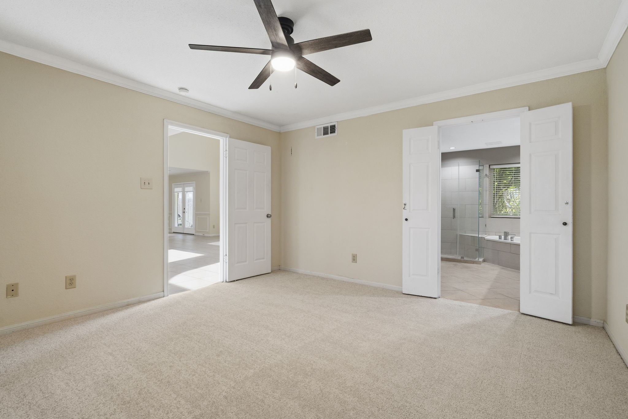 Double doors open to the primary bath, creating a spacious transition from the primary suite & adding to the rooms open feel.