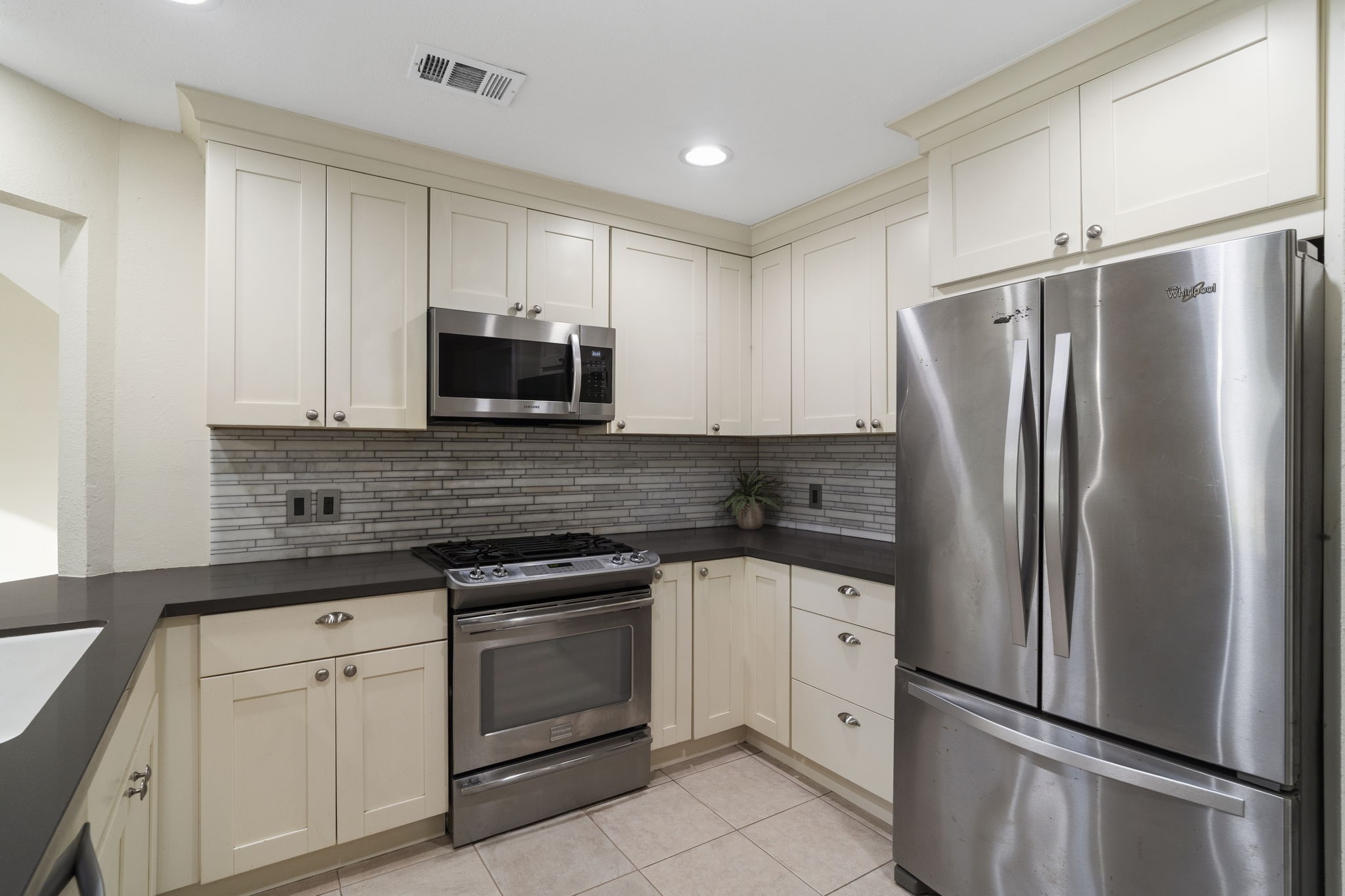 Shaker-style cabinetry extends to the ceiling, maximizing storage while giving the kitchen a clean, streamlined look.