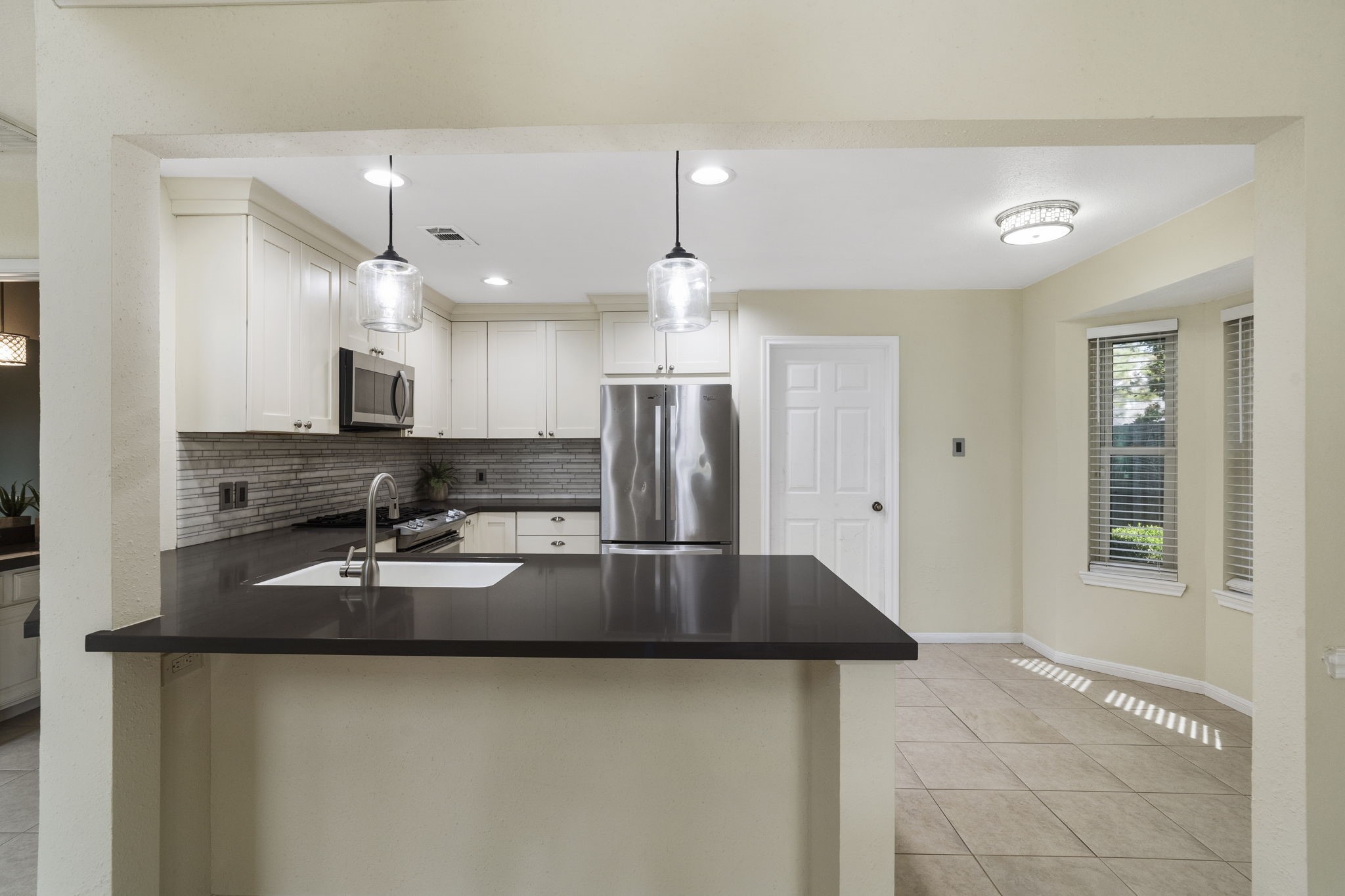 The kitchen features crisp white cabinetry, stainless steel appliances & generous counter space.