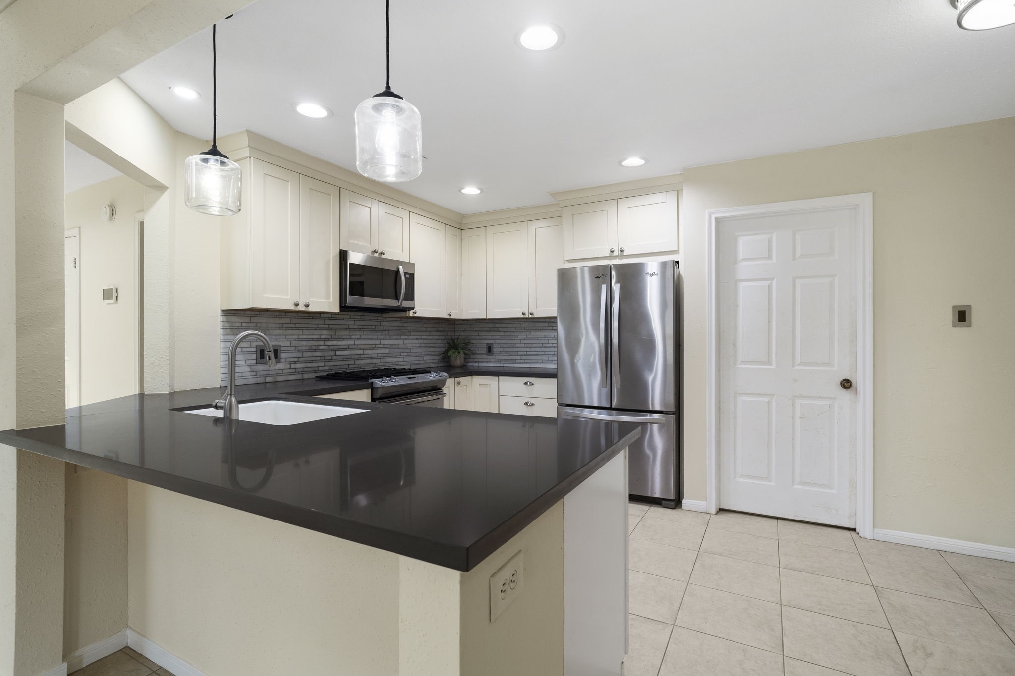 A closer look at the kitchen highlights the expansive breakfast bar, sleek countertops & abundant cabinetry, providing plenty of prep space & casual seating.