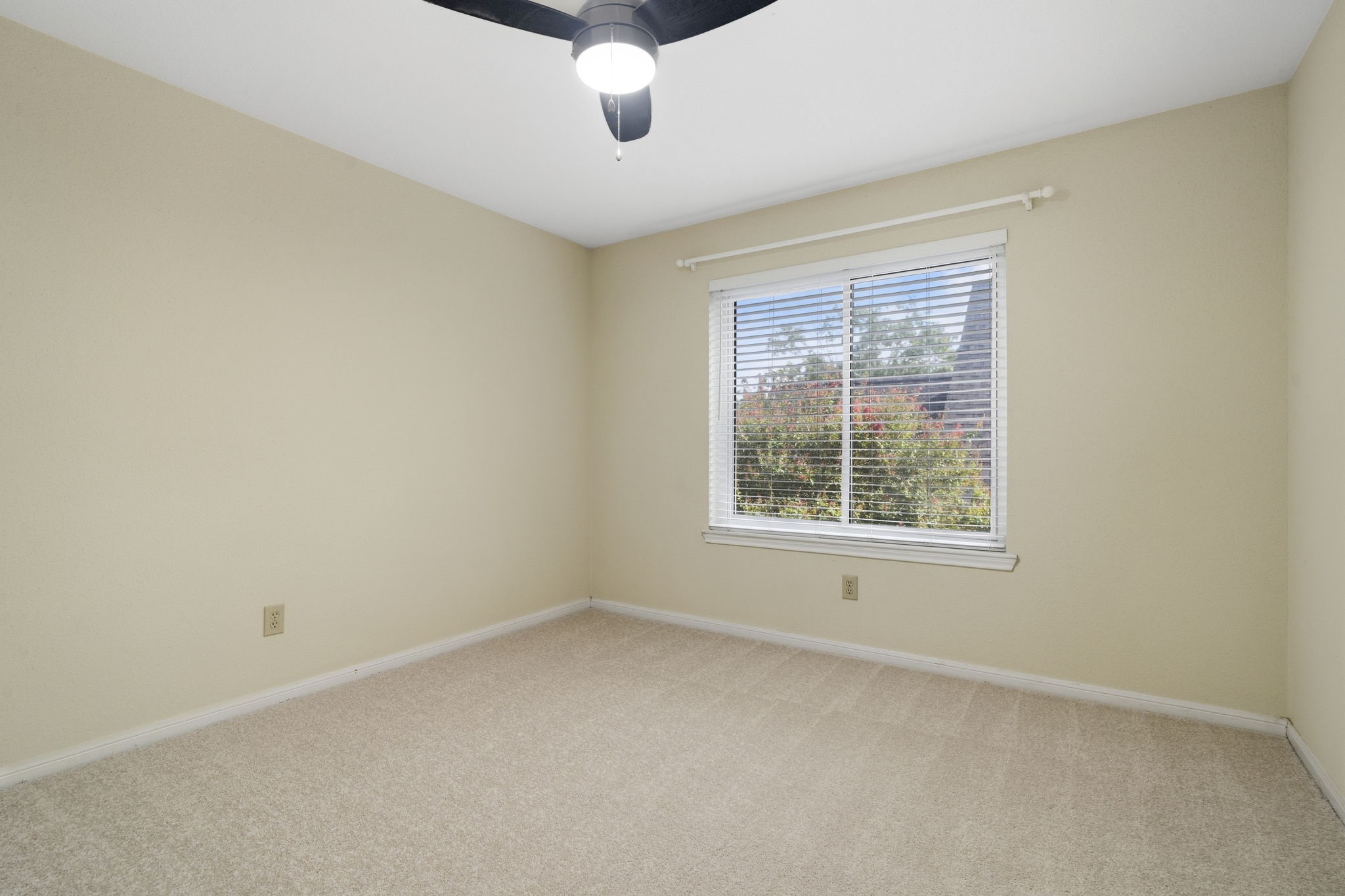 Another spacious secondary bedroom with a large window & ceiling fan.