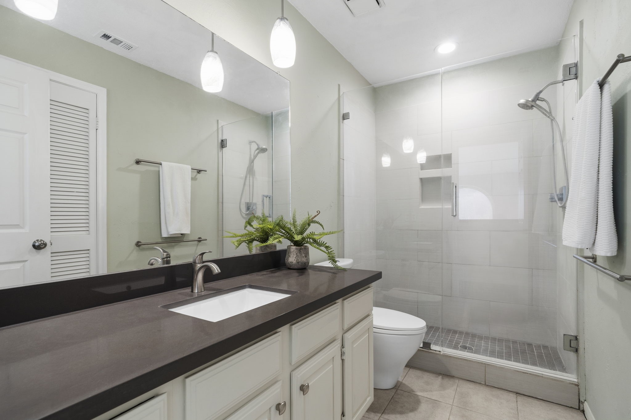 Updated secondary bath with a sleek frameless glass shower, modern tile & contemporary finishes.