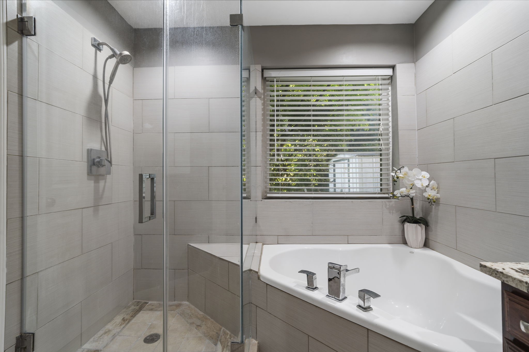 A frameless glass shower with floor-to-ceiling tile sits alongside the soaking tub, creating a clean & updated primary bath.