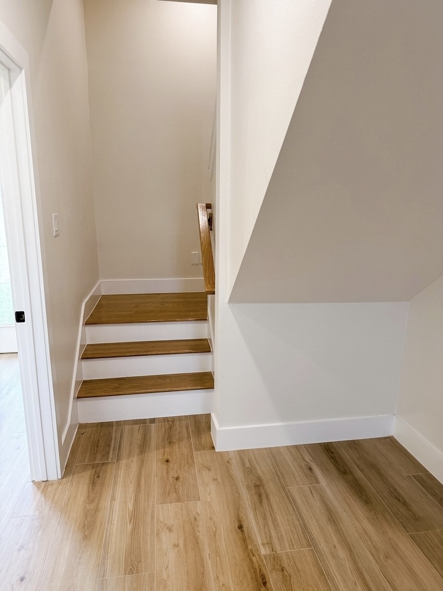 Charming staircase with warm porcelain flooring and clean white walls, offering a modern and inviting entrance.