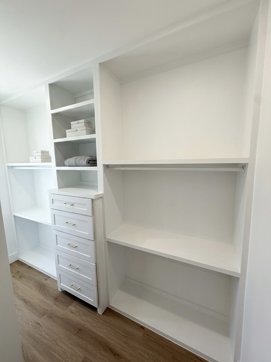 Spacious walk-in closet with custom shelving, ample storage, and elegant engineered hardwood flooring.
